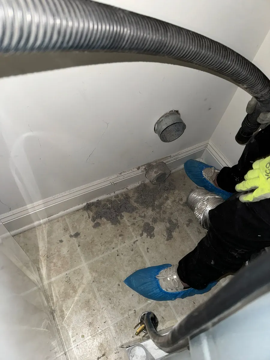 Technician using vacuum extraction equipment during a full-run dryer vent cleaning