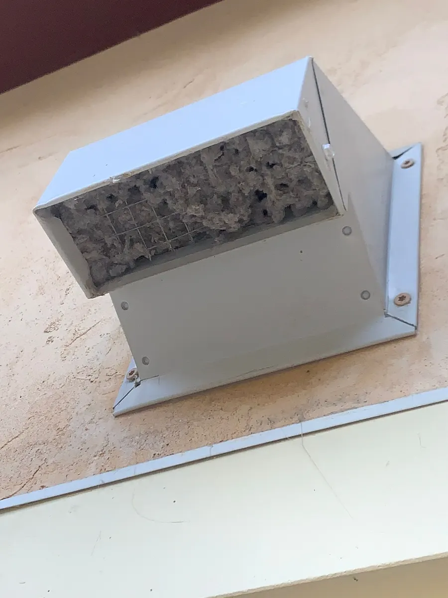 Exterior dryer vent hood clogged with built-up lint before cleaning