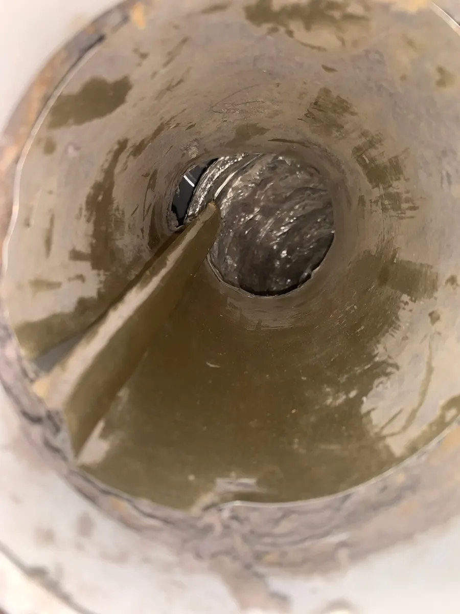 Interior of a round metal air duct caked with heavy dust and debris before cleaning