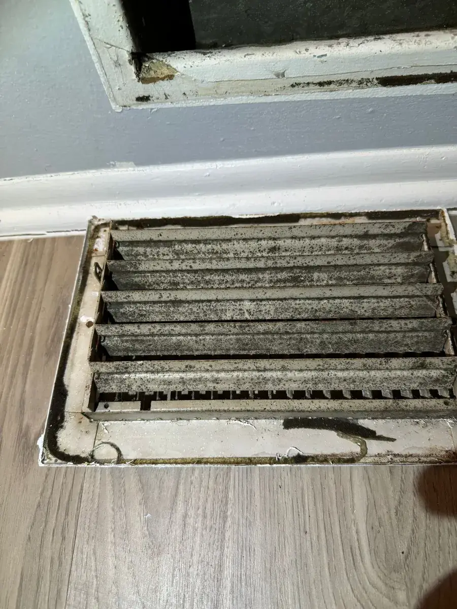 Floor return duct opening with heavy accumulated dust and debris before cleaning