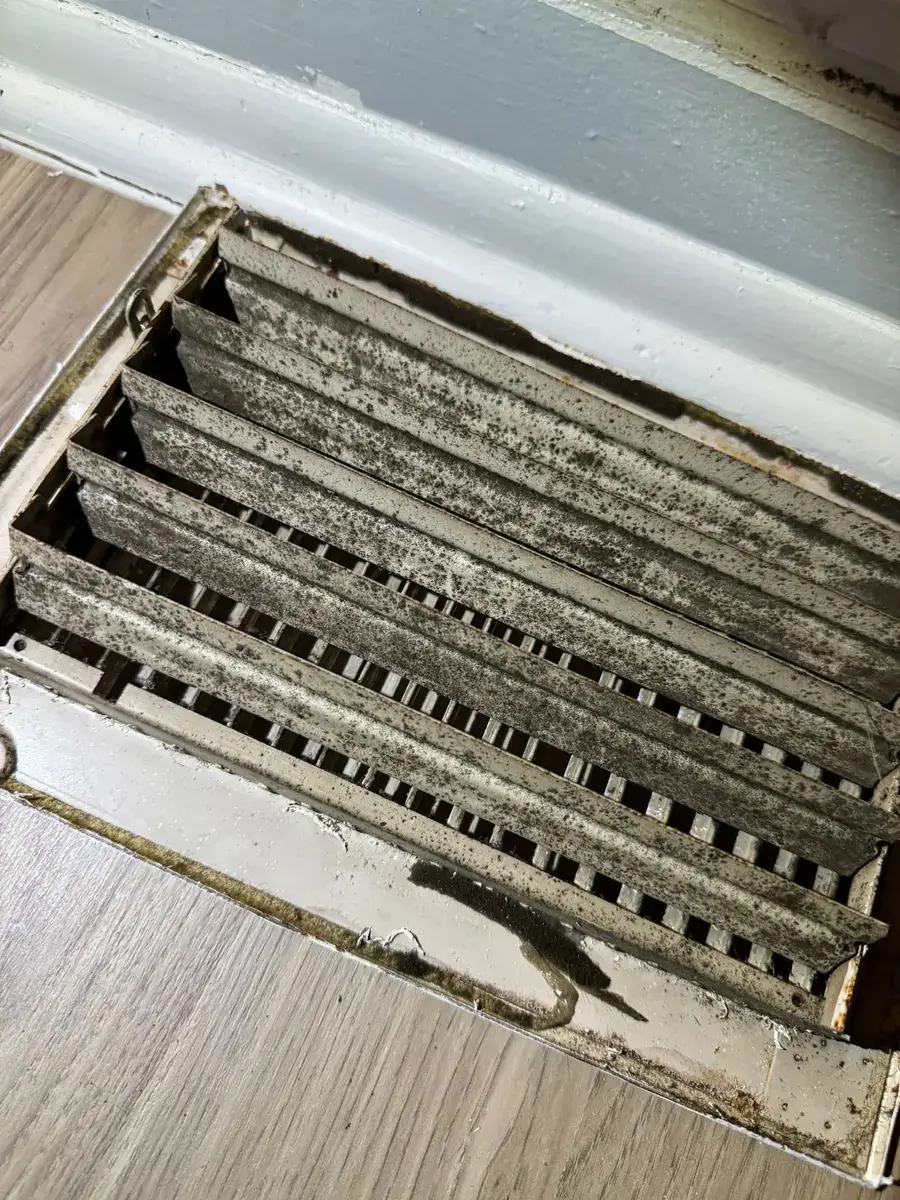 Dust and debris accumulated inside a floor return duct, upstream of where the HVAC filter sits