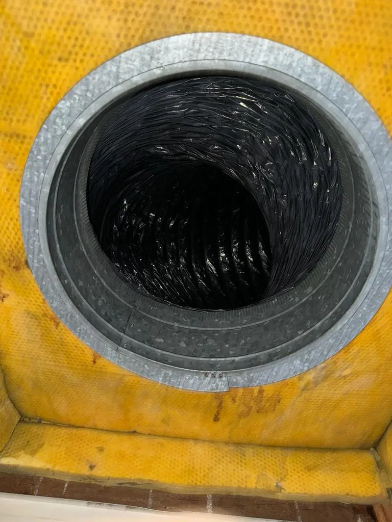 Inside of a flexible branch duct showing dust trapped in the ribbed lining before source-removal air duct cleaning
