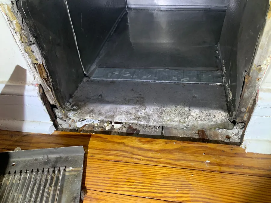 Trunk duct interior during cleaning, buildup partially removed showing bare metal emerging